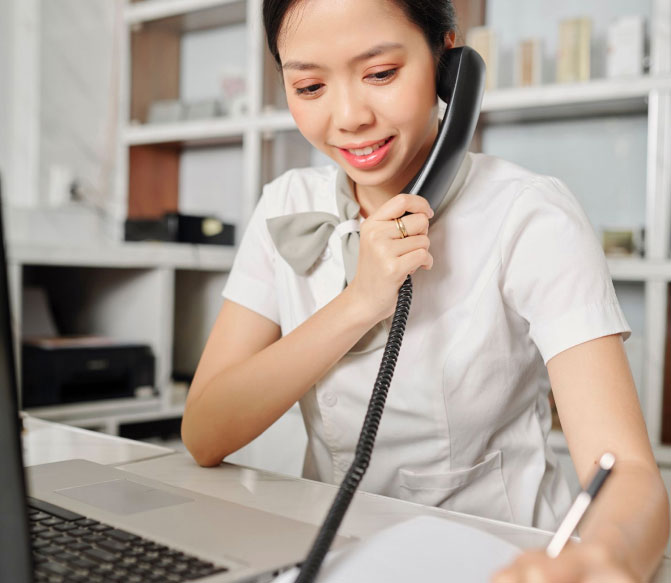Person Multitasking by Calling on a Telephone and Writing Notes While Working